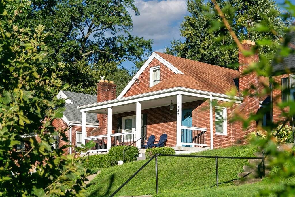 The Germantown Gem, a red brick home with a white columned porch and blue chairs in Louisville, Kentucky