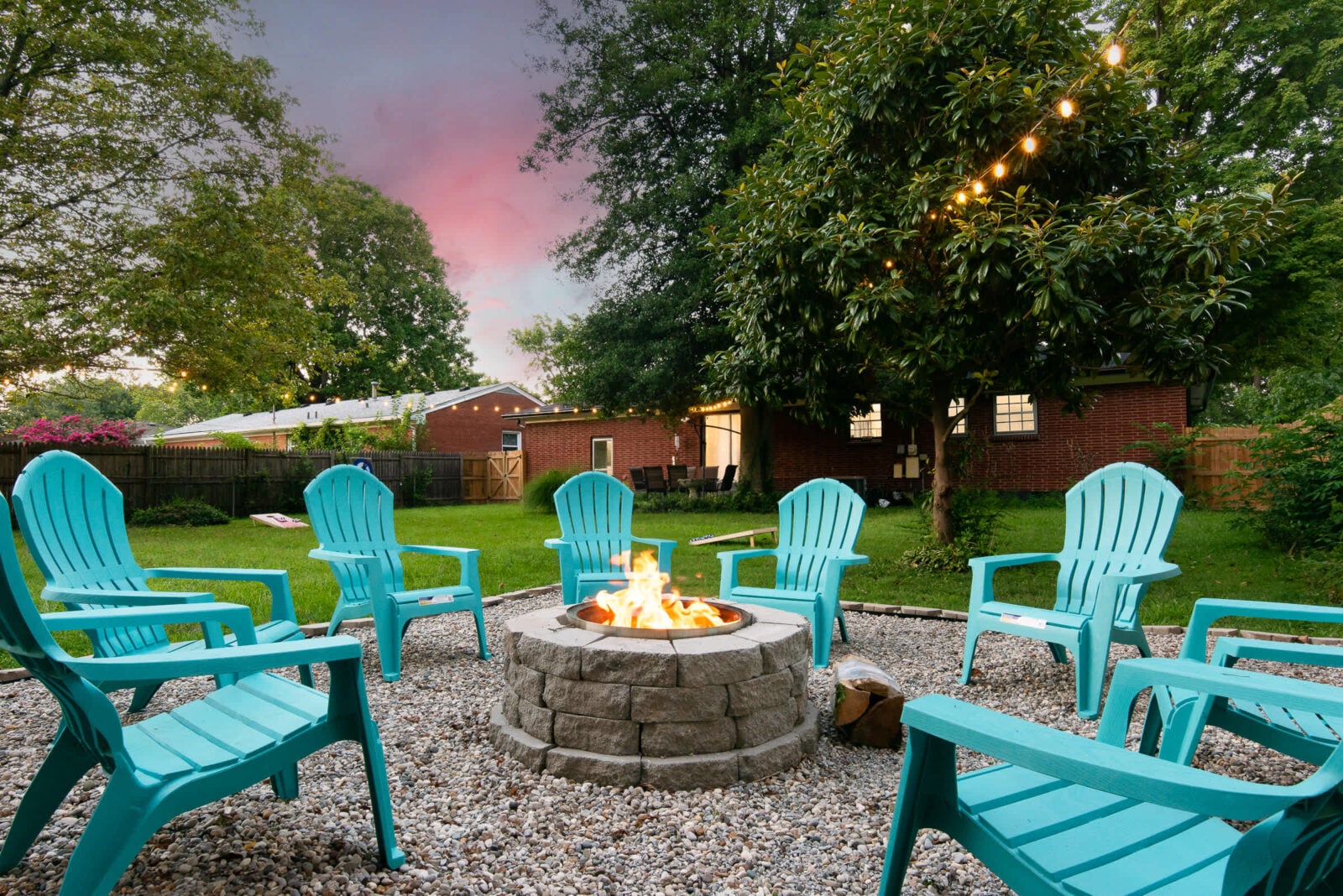 Hidden Gem with a lit fire pit, string lights and a cornhole set in Louisville, Kentucky