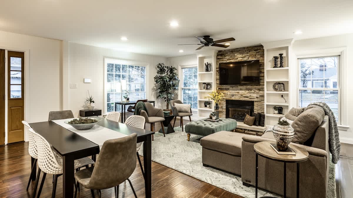 The Crestview Bungalow with a stacked stone fireplace, white built-in shelves and a long dining table in Indianapolis, Indiana