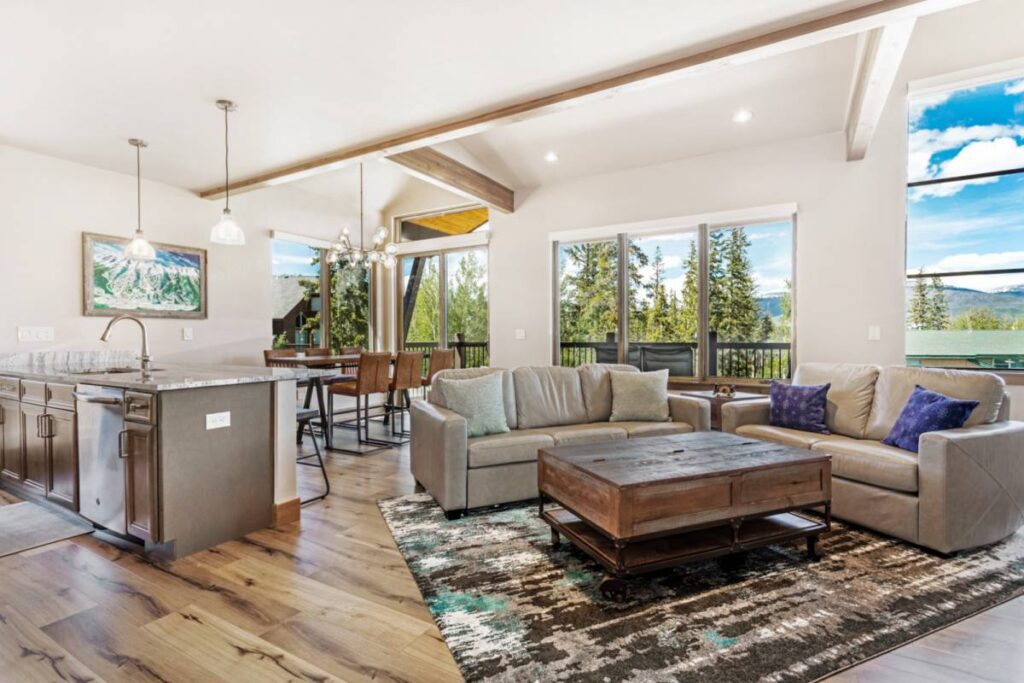 The Treehouse living room and kitchen island, with wide windows onto the evergreens in Silverthorne, Colorado