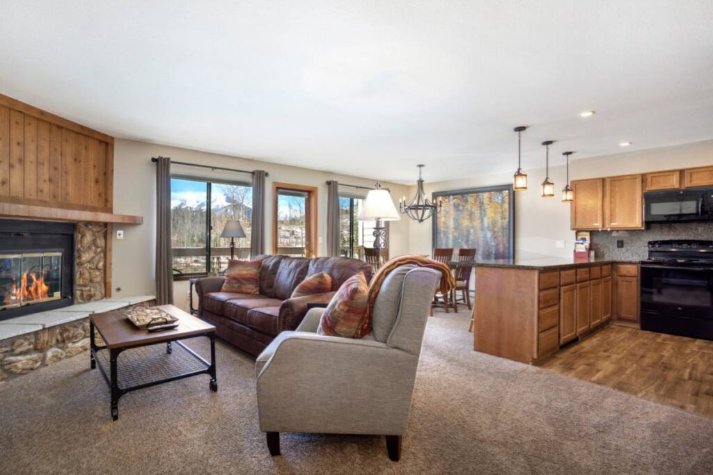 Nature Retreat living room with a stone fireplace, leather sofas and an open kitchen in Silverthorne, Colorado