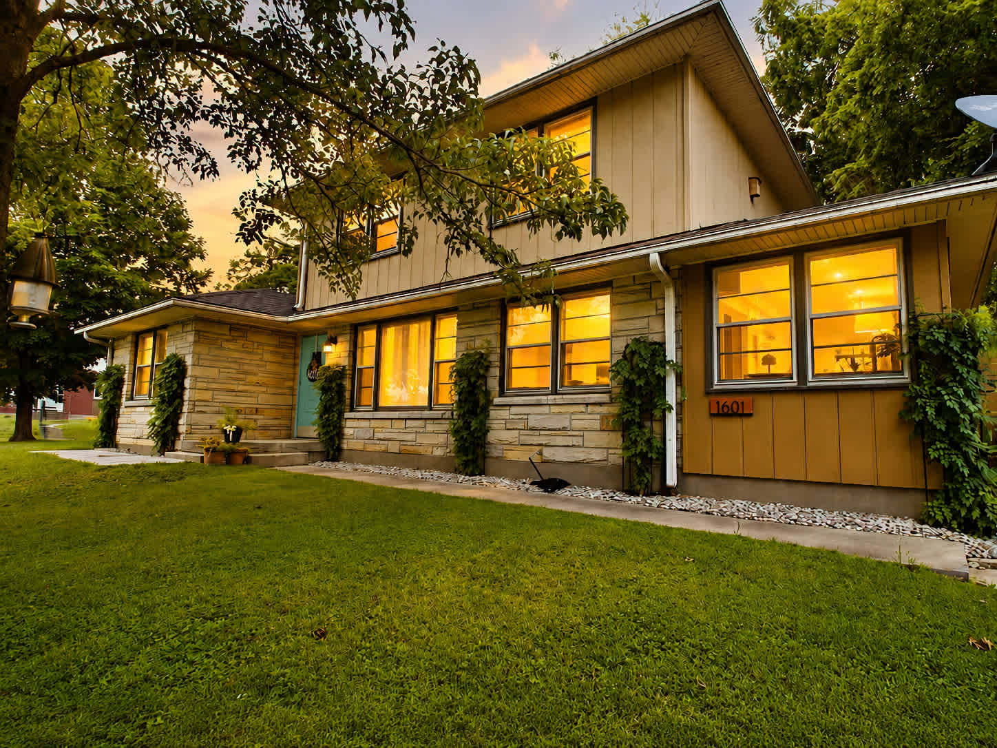 Casa Newburg, a stone and cedar home with warm lit windows at dusk in Louisville, Kentucky