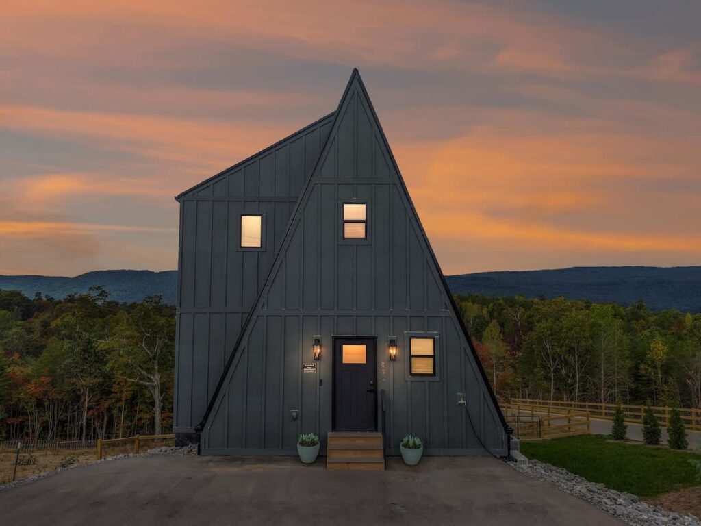 Sunset Peak, a dark A-frame with lit windows at sunset in Rossville, Georgia
